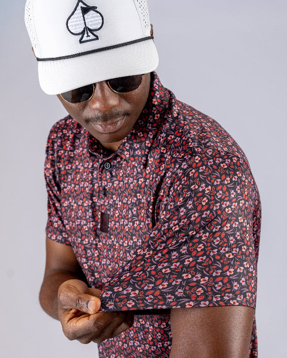 Men’s Shadow Rose golf polo by Pins & Aces featuring an all-over red and muted rose floral print on a black background with short sleeves and an athletic performance fit.