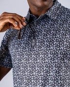 Men’s Shark Tooth golf polo by Pins & Aces featuring an all-over black, charcoal, gray, and white shark tooth-inspired micro print with short sleeves and an athletic performance fit.
