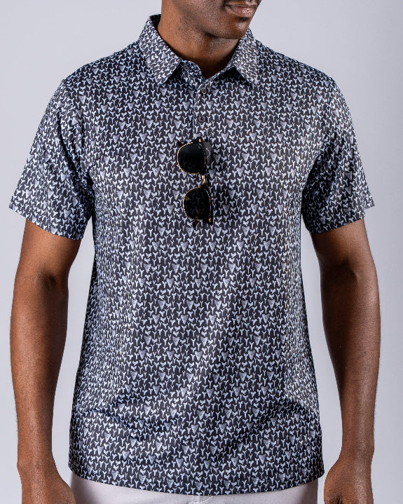 Men’s Shark Tooth golf polo by Pins & Aces featuring an all-over black, charcoal, gray, and white shark tooth-inspired micro print with short sleeves and an athletic performance fit.