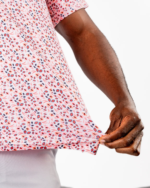 Men’s Soft Spoken golf polo by Pins & Aces featuring a subtle coral, red, navy, and white micro floral print with short sleeves and an athletic performance fit.