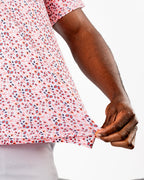 Men’s Soft Spoken golf polo by Pins & Aces featuring a subtle coral, red, navy, and white micro floral print with short sleeves and an athletic performance fit.