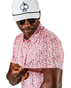 Men’s Soft Spoken golf polo by Pins & Aces featuring a subtle coral, red, navy, and white micro floral print with short sleeves and an athletic performance fit.
