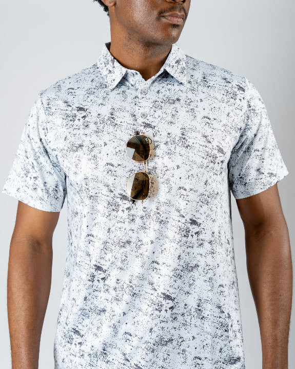 Men’s White Noise golf polo by Pins & Aces featuring a subtle white and gray abstract pattern, short sleeves, and an athletic performance fit.
