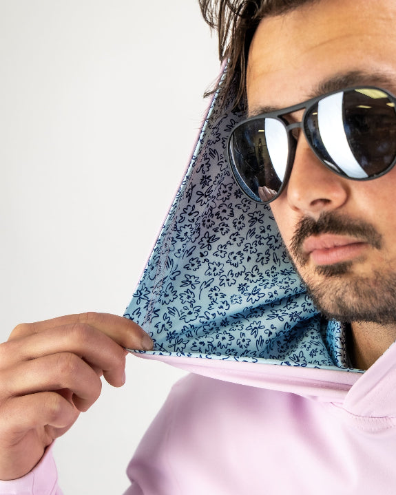 Men’s Flower Doodle Blue performance golf hoodie by Pins & Aces featuring a light pink body, blue floral doodle printed hood interior, embroidered spade logo, and long sleeves.