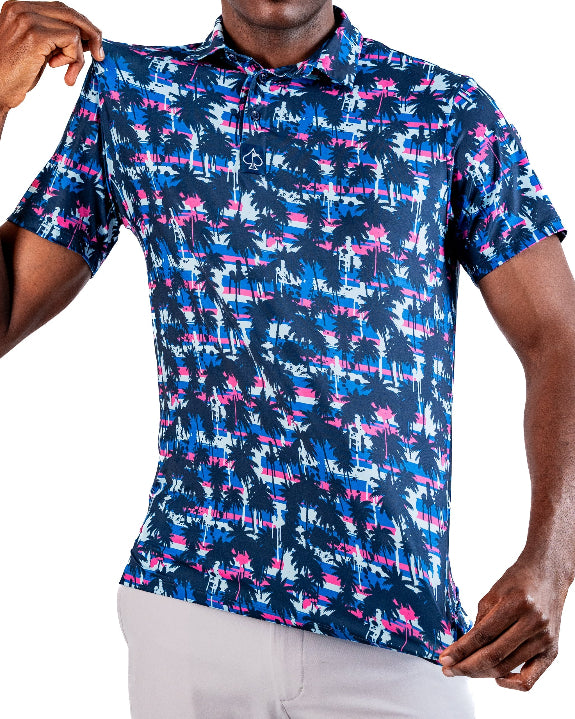 Men’s Palm Drip Dawn golf polo by Pins & Aces featuring navy palm trees over a blue, pink, and white tropical print with short sleeves and an athletic performance fit.