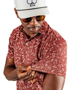 Men’s Autumn Bloom golf polo by Pins & Aces featuring a rust-colored all-over cream floral print, short sleeves, blade collar, and athletic performance fit.