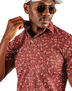 Men’s Autumn Bloom golf polo by Pins & Aces featuring a rust-colored all-over cream floral print, short sleeves, blade collar, and athletic performance fit.