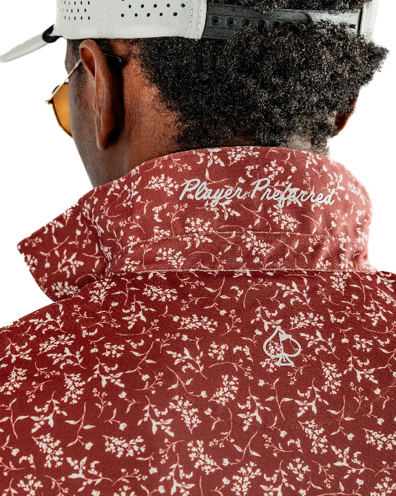 Men’s Autumn Bloom golf polo by Pins & Aces featuring a rust-colored all-over cream floral print, short sleeves, blade collar, and athletic performance fit.