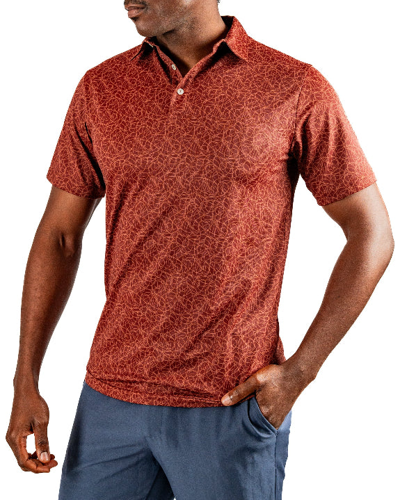 Men’s Filament golf polo by Pins & Aces featuring a rust and burnt orange abstract line pattern, short sleeves, modern blade collar, and athletic performance fit.