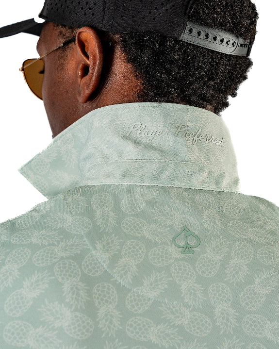 Men’s Pineapples Player Preferred golf polo by Pins & Aces featuring a sage green tonal pineapple print, blade collar, short sleeves, and athletic performance fit.