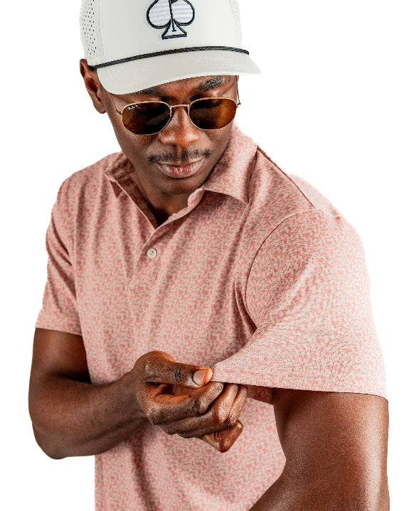Men’s Sparrows Player Preferred golf polo by Pins & Aces featuring a coral and cream micro-pattern, blade collar, short sleeves, and athletic performance fit.