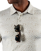 Men’s Drinking Buddies golf polo by Pins & Aces featuring a subtle drinking-inspired all-over print on a cream short-sleeve performance polo with an athletic fit.