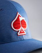 Blue Performance Spade golf hat by Pins & Aces featuring an embroidered Fairway Wave Spade logo, adjustable snapback, curved bill, and built-in magnetic golf ball marker holder.