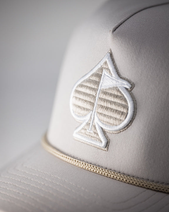 Bone off-white perforated rope golf hat by Pins & Aces featuring breathable perforated panels, braided rope detail, adjustable snapback, and built-in magnetic golf ball marker holder.