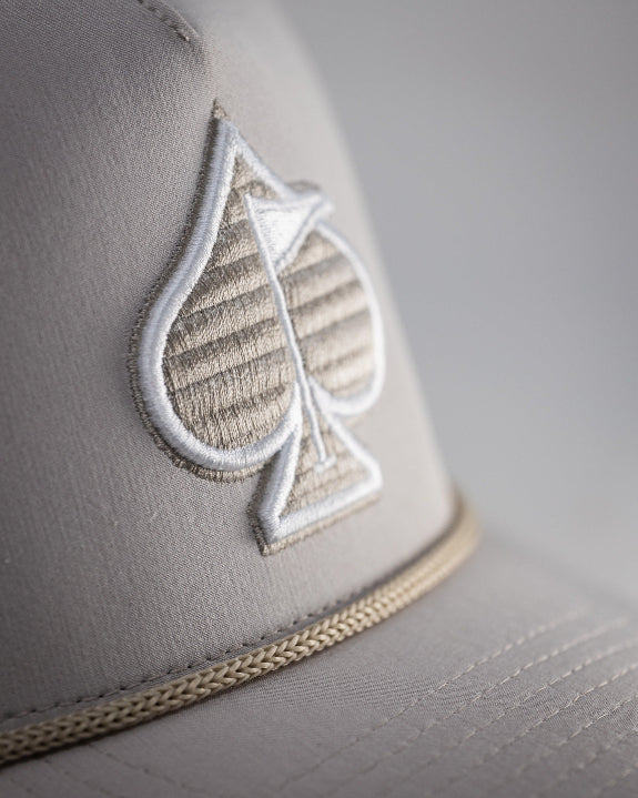 Bone off-white perforated rope golf hat by Pins & Aces featuring breathable perforated panels, braided rope detail, adjustable snapback, and built-in magnetic golf ball marker holder.