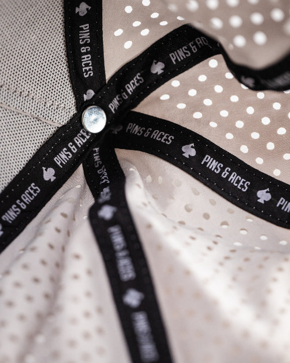 Bone off-white perforated rope golf hat by Pins & Aces featuring breathable perforated panels, braided rope detail, adjustable snapback, and built-in magnetic golf ball marker holder.