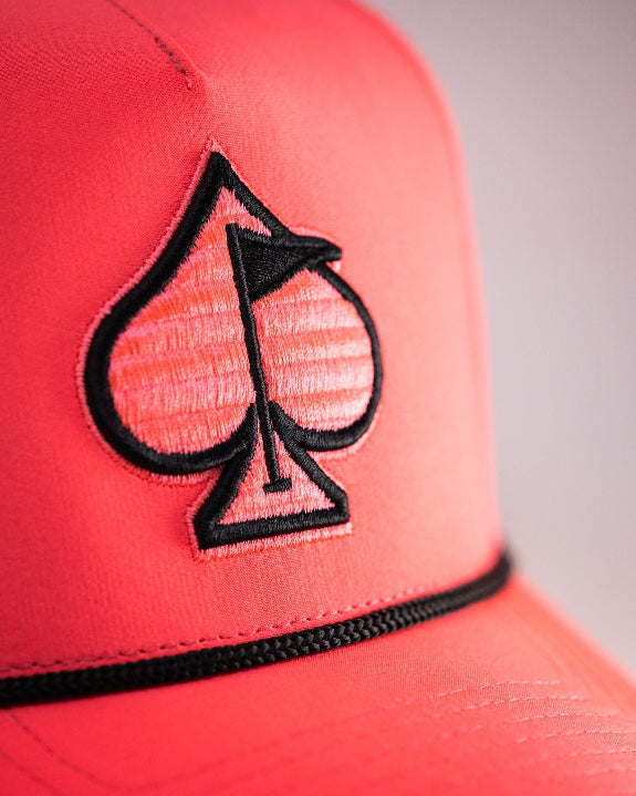 Highlighter pink perforated rope golf hat by Pins & Aces featuring an embroidered Fairway Wave Spade logo, adjustable snapback, and built-in magnetic golf ball marker holder.