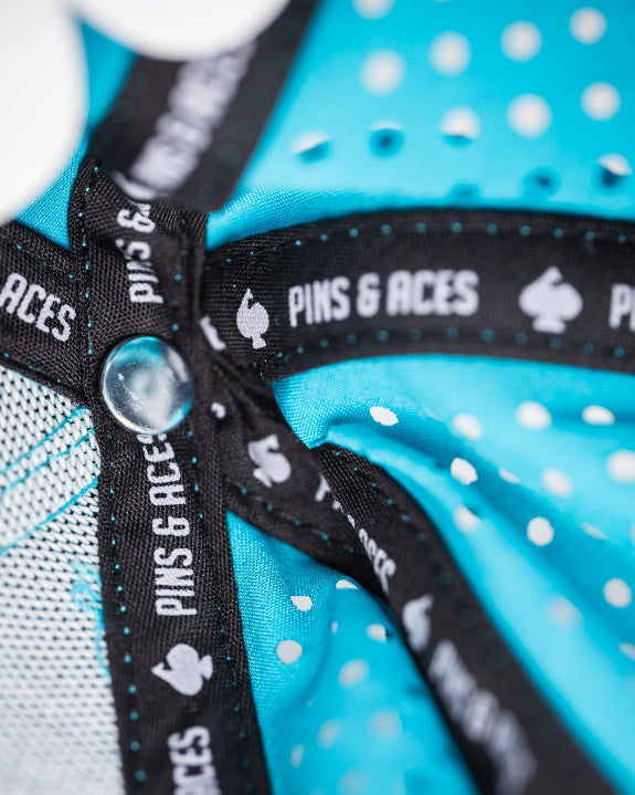 Baby blue perforated rope golf hat by Pins & Aces featuring a pink and white embroidered Fairway Wave Spade logo, white rope accent, perforated panels, and curved bill.