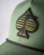 Olive green perforated rope golf hat by Pins & Aces featuring an embroidered Fairway Wave Spade logo, rope accent, adjustable snapback, and built-in magnetic golf ball marker holder.
