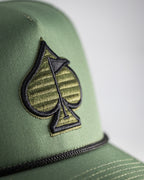 Olive green perforated rope golf hat by Pins & Aces featuring an embroidered Fairway Wave Spade logo, rope accent, adjustable snapback, and built-in magnetic golf ball marker holder.