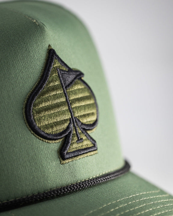 Olive green perforated rope golf hat by Pins & Aces featuring an embroidered Fairway Wave Spade logo, rope accent, adjustable snapback, and built-in magnetic golf ball marker holder.