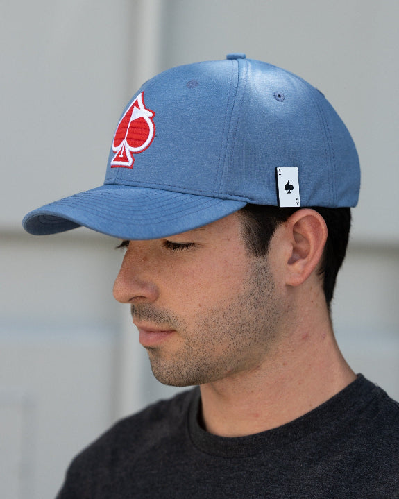 Blue Performance Spade golf hat by Pins & Aces featuring an embroidered Fairway Wave Spade logo, adjustable snapback, curved bill, and built-in magnetic golf ball marker holder.