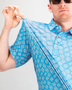 Men’s Skyline Dash Blue golf polo by Pins & Aces featuring a bright blue geometric dash pattern with pink accents and an athletic performance fit.