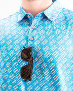 Men’s Skyline Dash Blue golf polo by Pins & Aces featuring a bright blue geometric dash pattern with pink accents and an athletic performance fit.