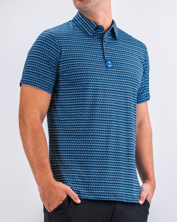 Men’s Rising Tides golf polo by Pins & Aces featuring a repeating blue and navy wave-inspired pattern, short sleeves, and an athletic performance fit.