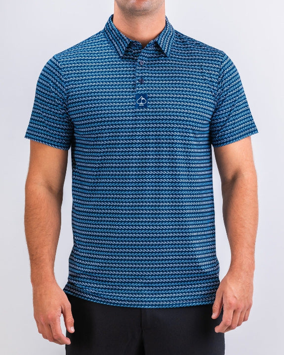 Men’s Rising Tides golf polo by Pins & Aces featuring a repeating blue and navy wave-inspired pattern, short sleeves, and an athletic performance fit.