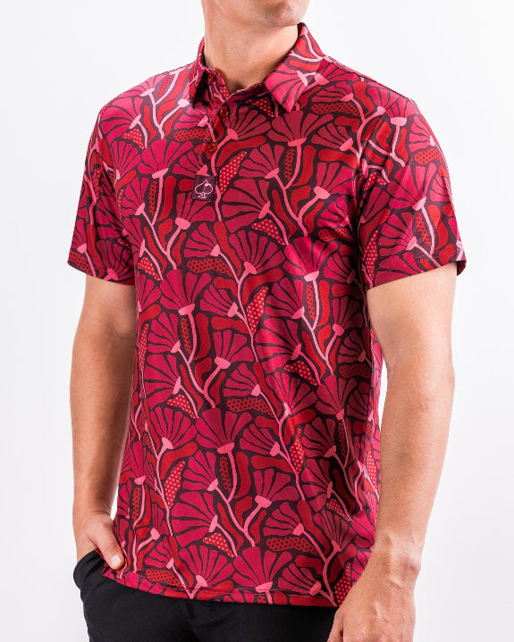 Men’s Garden Party Crimson Bloom golf polo by Pins & Aces featuring an oversized crimson, red, pink, and burgundy floral print with short sleeves and an athletic performance fit.