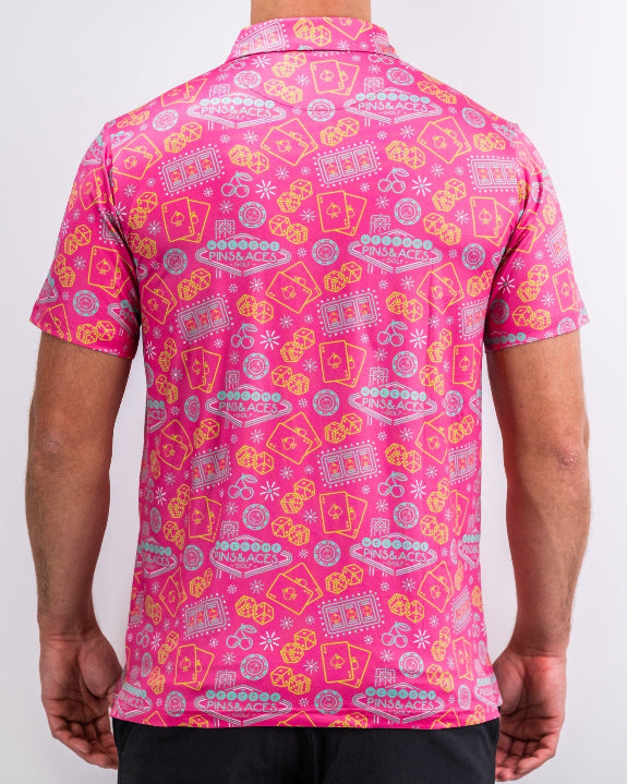 Men’s Big Ace Fuchsia golf polo by Pins & Aces featuring a bright pink casino print with playing cards, dice, poker chips, slot machines, and an athletic performance fit.