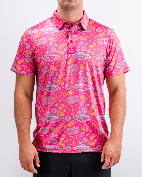 Men’s Big Ace Fuchsia golf polo by Pins & Aces featuring a bright pink casino print with playing cards, dice, poker chips, slot machines, and an athletic performance fit.