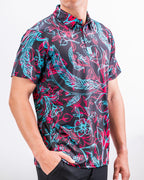 Men’s Cabo Electric golf polo by Pins & Aces featuring an aqua, hot pink, and coral tropical floral and leaf print on a dark charcoal background with an athletic performance fit.