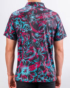Men’s Cabo Electric golf polo by Pins & Aces featuring an aqua, hot pink, and coral tropical floral and leaf print on a dark charcoal background with an athletic performance fit.