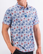 Men’s Hibiscus Harmony golf polo by Pins & Aces featuring blue and coral hibiscus flowers on a white lightweight performance golf shirt.