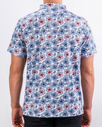 Men’s Hibiscus Harmony golf polo by Pins & Aces featuring blue and coral hibiscus flowers on a white lightweight performance golf shirt.