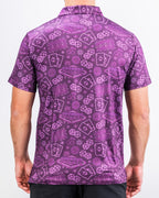 Men’s purple casino golf polo by Pins & Aces featuring an all-over pattern of playing cards, dice, poker chips, slot machines, and Las Vegas-inspired graphics.