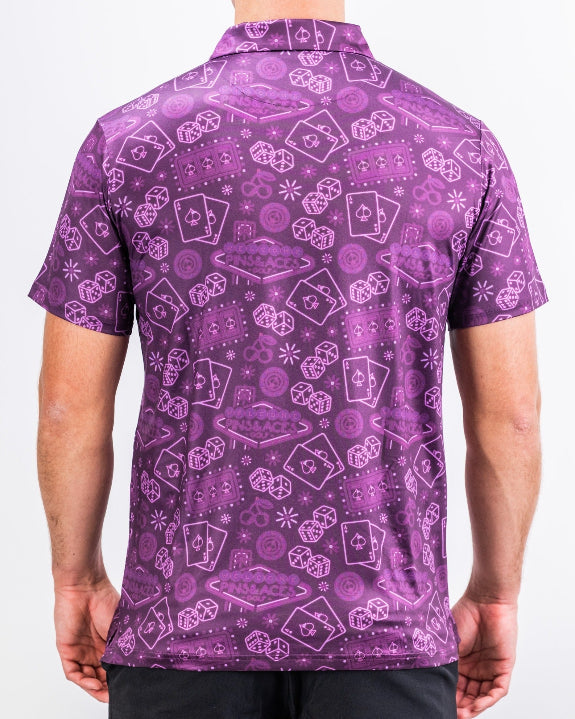 Men’s purple casino golf polo by Pins & Aces featuring an all-over pattern of playing cards, dice, poker chips, slot machines, and Las Vegas-inspired graphics.