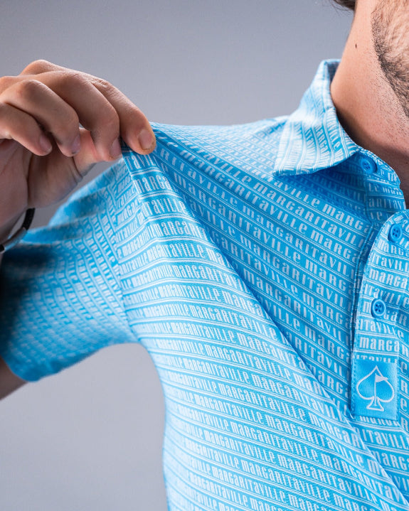 Men’s Margaritaville Rendezvous performance golf polo by Pins & Aces featuring a bright blue all-over pattern, short sleeves, collared neckline, and athletic fit.