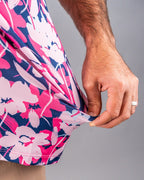 Men’s Brushed Flowers golf polo by Pins & Aces featuring a bold pink, blush, white, blue, and navy floral print with short sleeves and an athletic performance fit.