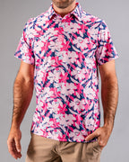 Men’s Brushed Flowers golf polo by Pins & Aces featuring a bold pink, blush, white, blue, and navy floral print with short sleeves and an athletic performance fit.