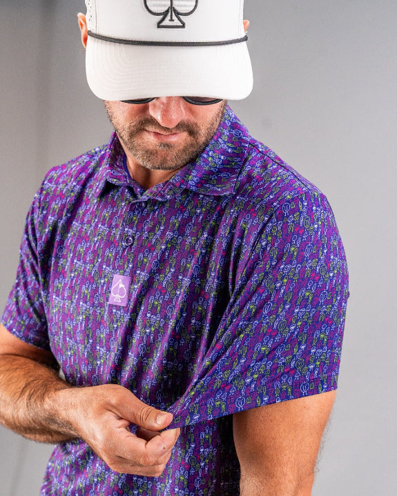 Men’s Doodle Guy Purple golf polo by Pins & Aces featuring an all-over purple, violet, blue, and green doodle-inspired pattern with short sleeves and an athletic performance fit.
