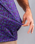 Men’s Doodle Guy Purple golf polo by Pins & Aces featuring an all-over purple, violet, blue, and green doodle-inspired pattern with short sleeves and an athletic performance fit.