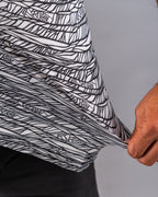 Men’s Fragment Black golf polo by Pins & Aces featuring an all-over black, white, and gray abstract line pattern with short sleeves and an athletic performance fit.