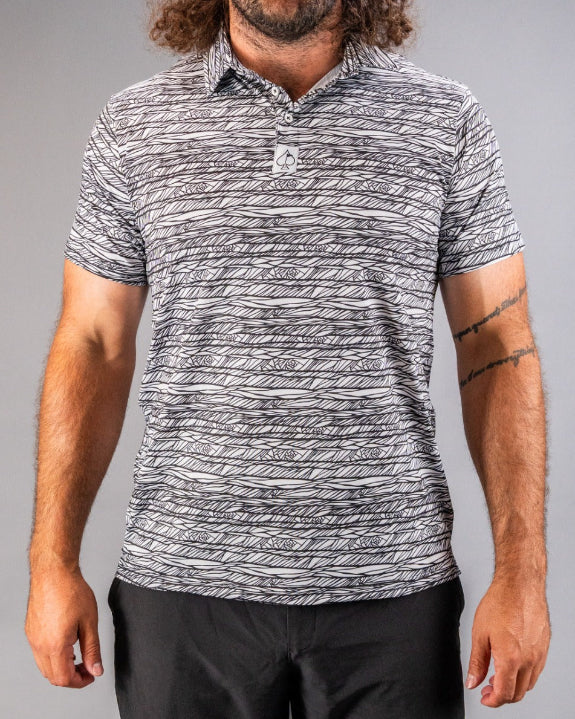 Men’s Fragment Black golf polo by Pins & Aces featuring an all-over black, white, and gray abstract line pattern with short sleeves and an athletic performance fit.