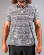 Men’s Fragment Black golf polo by Pins & Aces featuring an all-over black, white, and gray abstract line pattern with short sleeves and an athletic performance fit.