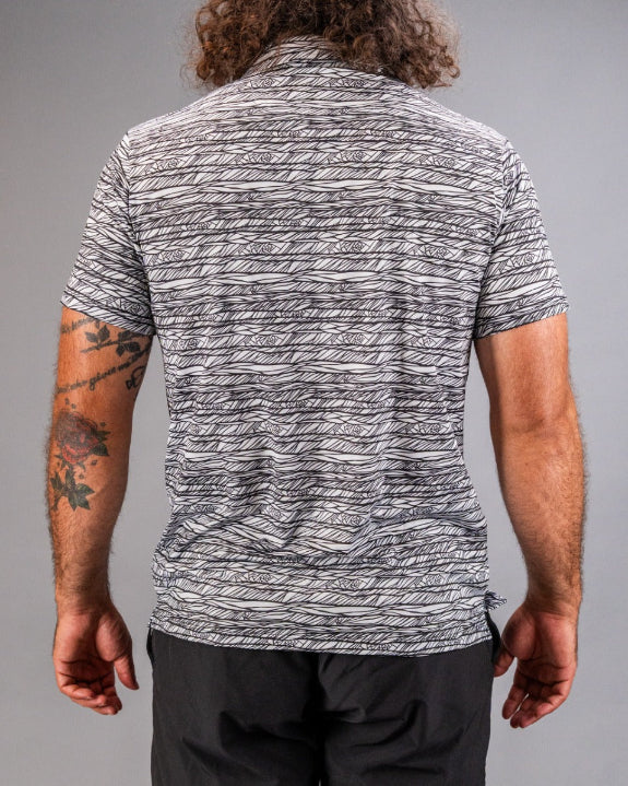 Men’s Fragment Black golf polo by Pins & Aces featuring an all-over black, white, and gray abstract line pattern with short sleeves and an athletic performance fit.