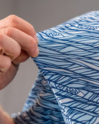 Men’s Fragment Blue golf polo by Pins & Aces featuring an all-over abstract fragmented line pattern in blue and white with short sleeves and an athletic performance fit.