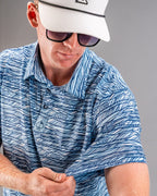 Men’s Fragment Blue golf polo by Pins & Aces featuring an all-over abstract fragmented line pattern in blue and white with short sleeves and an athletic performance fit.